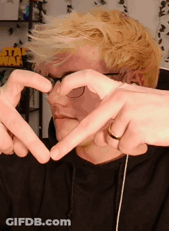 A Man Making A Heart Shape With His Hands In Front Of A Sign That Says Star Wars GIF