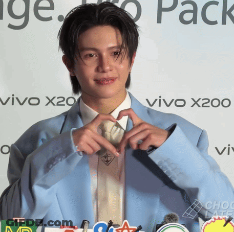 A Man Making A Heart Shape With His Hands In Front Of A Vivo X200 Sign GIF