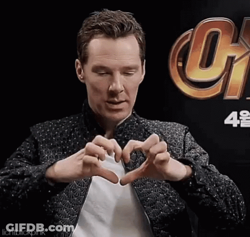A Man Making A Heart With His Hands In Front Of A Sign That Says Infinity War GIF