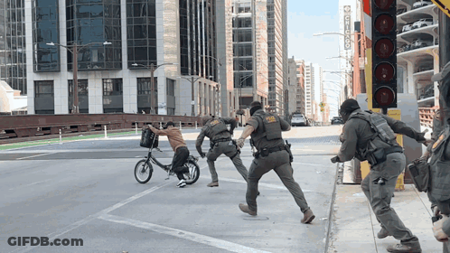 A Man On A Bike Is Being Chased By Police Officers GIF