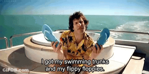 A Man On A Boat Holding Flip Flops And Saying I Got My Swimming Trunks And My Flippy Floppies . GIF