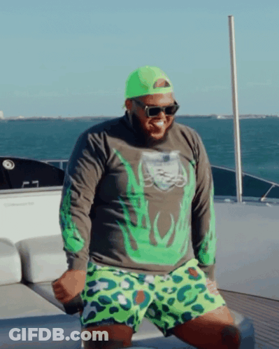 A Man On A Boat Wearing A Green Shirt And Leopard Print Shorts GIF