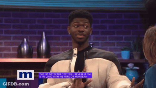 A Man On A Tv Show Talking To A Woman With The Letter M On The Bottom Right GIF