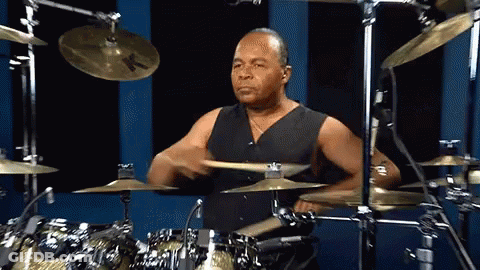 A Man Playing A Drum Set With A Cymbal That Says K On It GIF