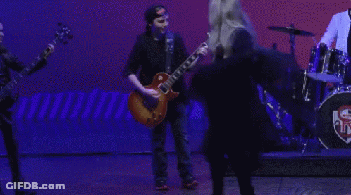 A Man Playing A Guitar And A Woman Singing On A Stage GIF
