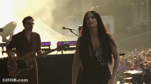 A Man Playing A Guitar And A Woman Singing On Stage GIF