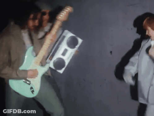 A Man Playing A Guitar And Holding A Boom Box GIF
