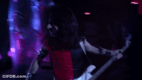 A Man Playing A Guitar In A Dark Room GIF