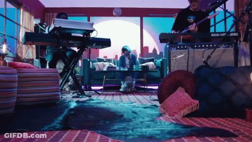A Man Playing A Guitar In A Living Room With A Fender Amplifier GIF