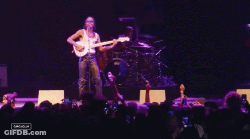 A Man Playing A Guitar In Front Of A Crowd With A Sign That Says Cancella GIF