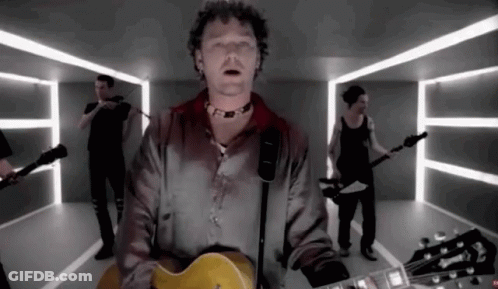 A Man Playing A Guitar In Front Of A Group Of People GIF