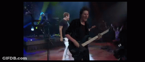 A Man Playing A Guitar In Front Of A Group Of People GIF