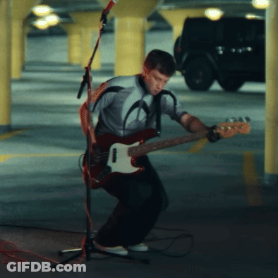 A Man Playing A Guitar In Front Of A Microphone GIF