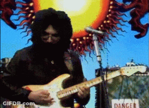A Man Playing A Guitar In Front Of A Sign That Reads Danger GIF