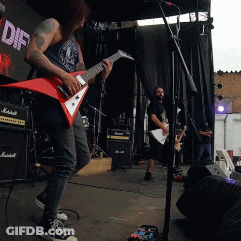 A Man Playing A Guitar In Front Of A Sign That Says Diff GIF