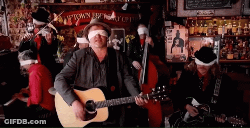 A Man Playing A Guitar In Front Of A Sign That Says Ptown Brewery Co GIF