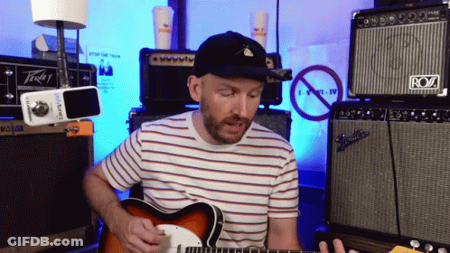 A Man Playing A Guitar In Front Of An Amp That Says Roz GIF
