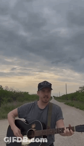 A Man Playing A Guitar On A Dirt Road With The Name Josiah And The Bonnevilles Written Below Him GIF