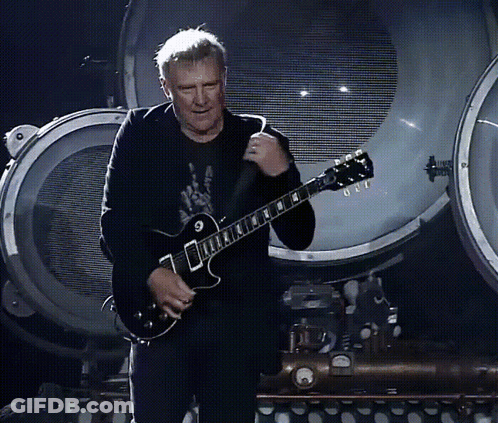 A Man Playing A Guitar With The Letter G On The Neck GIF