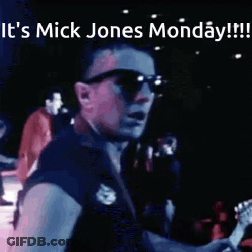 A Man Playing A Guitar With The Words It 'S Mick Jones Monday Written Above Him GIF