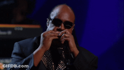A Man Playing A Harmonica In Front Of A Keyboard That Says Yamaha GIF