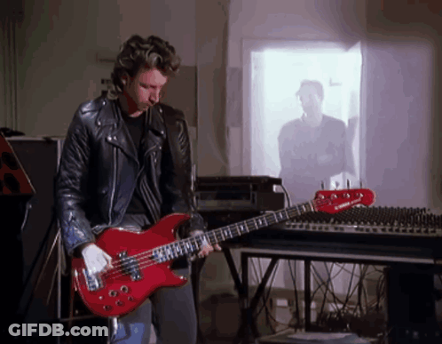 A Man Playing A Red Bass Guitar In Front Of A Yamaha Mixer GIF