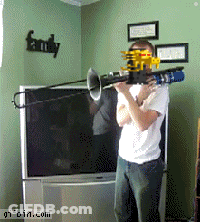 A Man Playing A Trombone In Front Of A Tv With A Family Sign On The Wall GIF