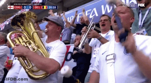 A Man Playing A Tuba In Front Of A Sign That Says Fifa World Cup GIF