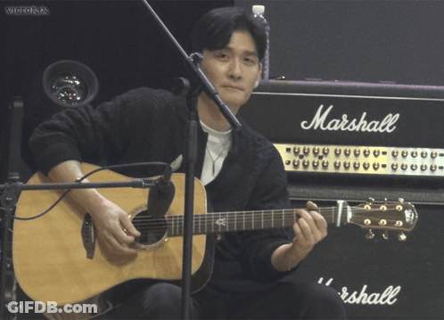 A Man Playing An Acoustic Guitar In Front Of A Marshall Amplifier GIF