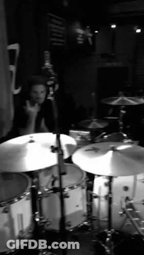 A Man Playing Drums In A Black And White Photo With The Number 7 In The Background GIF