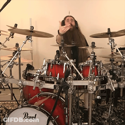 A Man Playing Drums With A Pearl Drum Set In The Foreground GIF