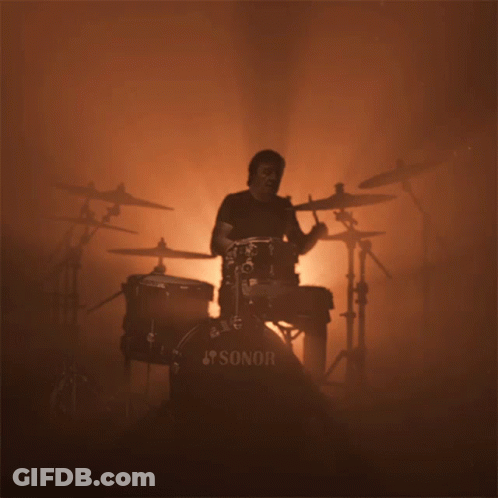 A Man Playing Drums With A Sonor Drum Set In The Foreground GIF