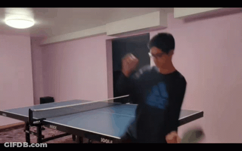 A Man Playing Ping Pong With A Joola Table In The Background GIF