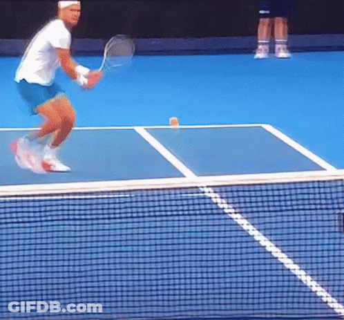 A Man Playing Tennis On A Blue Court With A Yellow Ball On The Court GIF