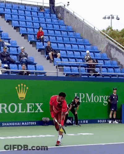 A Man Playing Tennis On A Court With A Rolex Ad Behind Him GIF