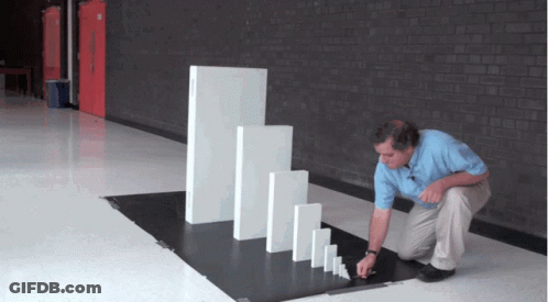 A Man Playing With Dominoes In A Hallway With A Brick Wall GIF