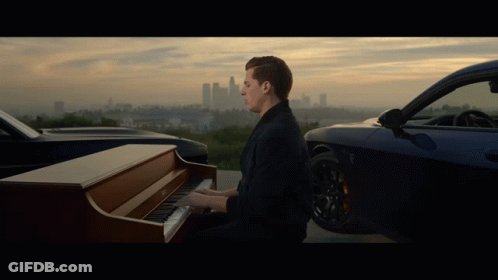 A Man Plays A Piano In Front Of A Car GIF