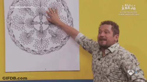 A Man Pointing At A Drawing On A Yellow Wall With The Words All Abajo On The Bottom GIF