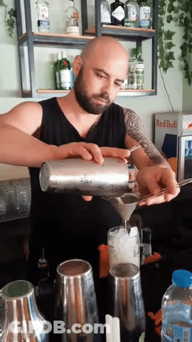 A Man Pouring A Drink In Front Of A Red Bull Cooler GIF