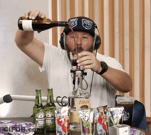 A Man Pouring A Drink Into A Glass From A Bottle Of Tito 'S GIF
