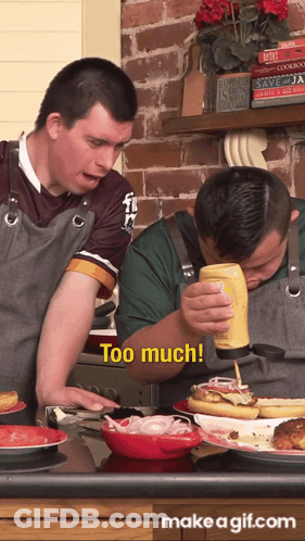 A Man Pouring Mustard On A Hot Dog While Another Man Looks On And Says Too Much GIF