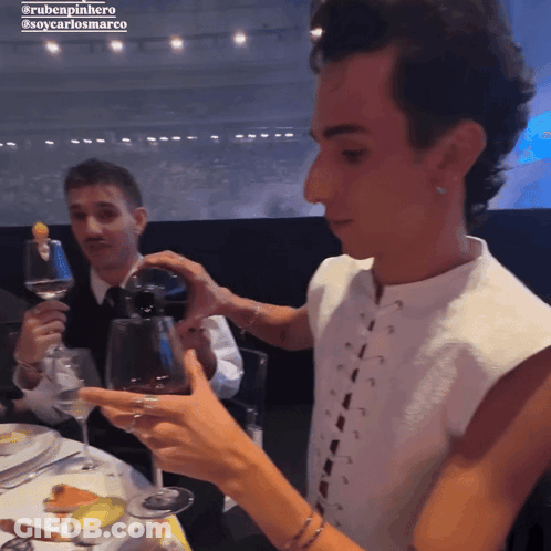 A Man Pouring Wine Into A Glass With The Name Rubenpinheiro On The Bottom Right GIF