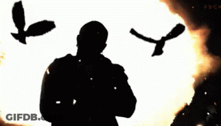 A Man Praying In Front Of A Fire With Birds Flying Around Him GIF