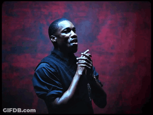 A Man Praying With His Hands Folded In Front Of A Red Background GIF