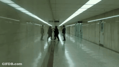 A Man Pushing Another Man In A Hallway With The Words Uuuu Written On The Floor GIF