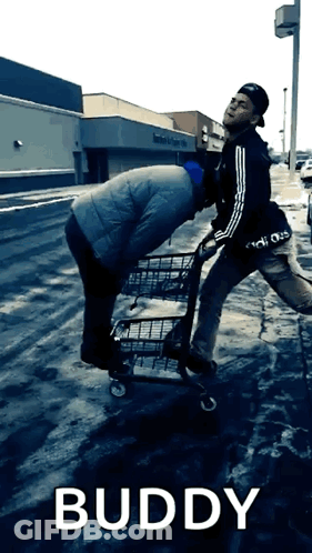 A Man Pushing Another Man In A Shopping Cart With The Word Buddy Below Him GIF