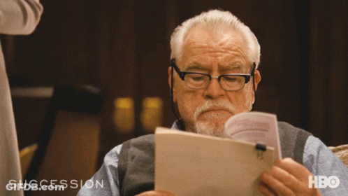 A Man Reading A Book With The Word Succession On The Bottom Left GIF