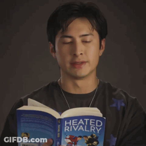 A Man Reads A Book Called Heated Rivalry GIF