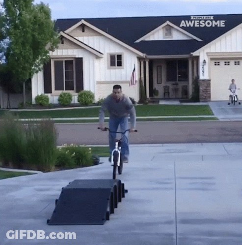 A Man Rides A Bike Down A Ramp In Front Of A House That Says Awesome GIF