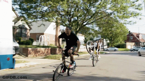 A Man Riding A Bike On A Street Next To A White Van That Says ' Ice Cream ' On It GIF
